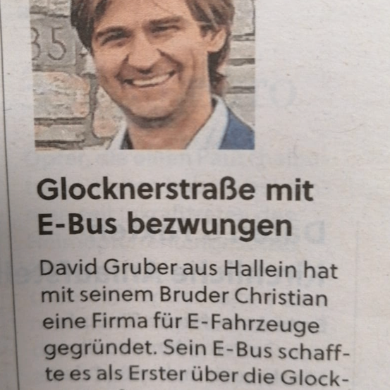 Ein lächelnder Mann ist abgebildet mit einer Überschrift über die Glocknerstraße, die von einem E-Bus durchquert wird. David Gruber aus Hallein hat mit seinem Bruder Christian eine Firma für E-Fahrzeuge gegründet. Ihr E-Bus war der erste, der die Glocknerstraße überquerte.