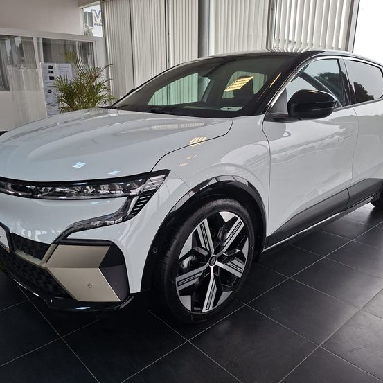 Ein weißer SUV mit modernem Design steht in einem Ausstellungsraum mit schwarzen Fliesenboden. Er hat einen schlanken vorderen Stoßfänger und Chrom-Akzente.