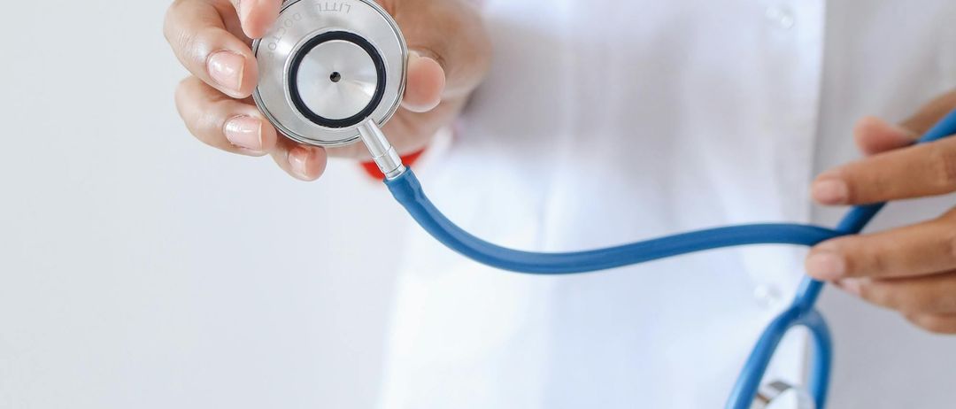 Ein Arzt hält ein Stethoskop in beiden Händen und bereitet sich möglicherweise darauf vor, es zu benutzen, um das Herzklopfen oder die Lungen eines Patienten zu hören.