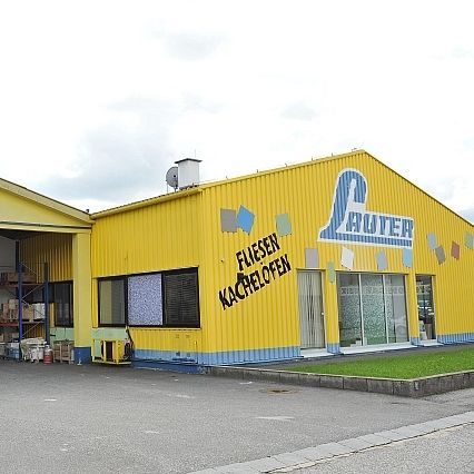 Ein gelbes Gebäude mit Lauter drauf, zwei Garagen und ein Geschäft mit dem Wort Fliesen an der Wand.