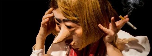 Eine Person mit Maske hält eine Zigarette in einer Hand und stützt den Kopf mit der anderen, umgeben von Rauch.