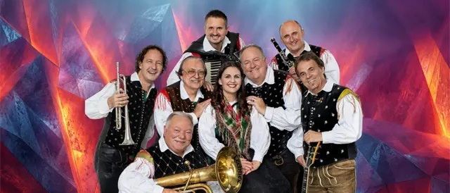 Eine Gruppe von Musikern in traditionellen Kostümen posiert mit verschiedenen Instrumenten für ein Foto.