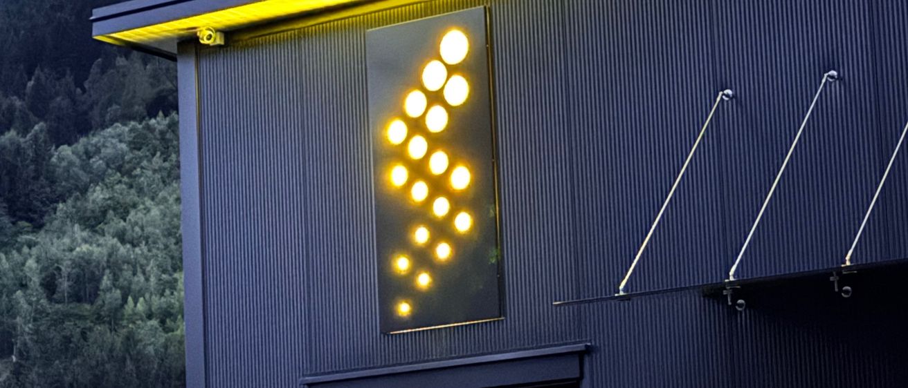 Ein schwarzes Gebäude mit einer gelben Lichtanzeige an der Seite. Die Nummer 293 befindet sich an der Tür, und darüber befindet sich ein Schild. Das Fenster hat Jalousien.