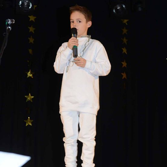 Bild enthält, Performer, Person, Solo Performance, Boy, Child, Male, Face, Crowd, Coat, Microphone