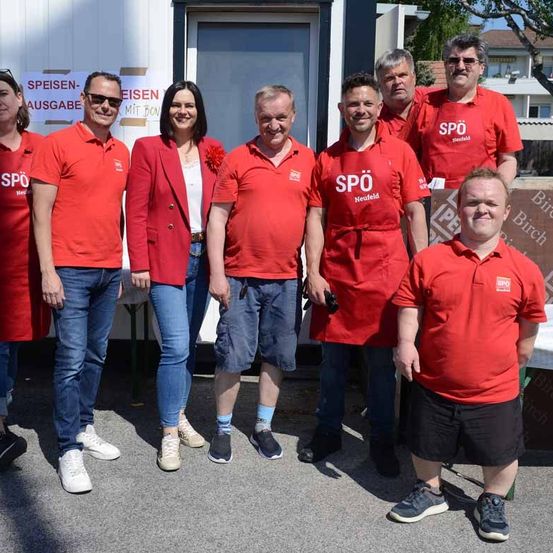 Eine Gruppe von Menschen in roten Polo-Shirts mit der Aufschrift 'SPO Neufeld' steht draußen.