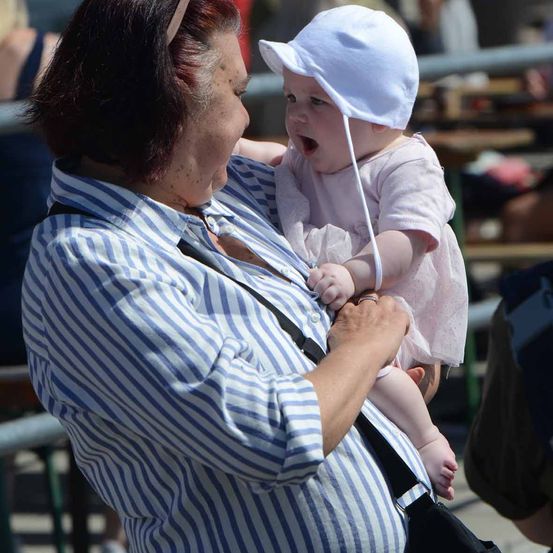 Eine Frau in einem gestreiften Shirt hält ein Babymädchen in einer weißen Mütze.