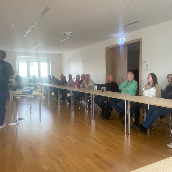 Eine Gruppe von Menschen sitzt um einen langen Tisch in einem Konferenzraum und diskutiert.