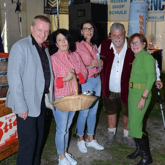 Fünf Erwachsene stehen bei einem Festival zusammen. Sie alle lächeln und schauen in die Kamera.