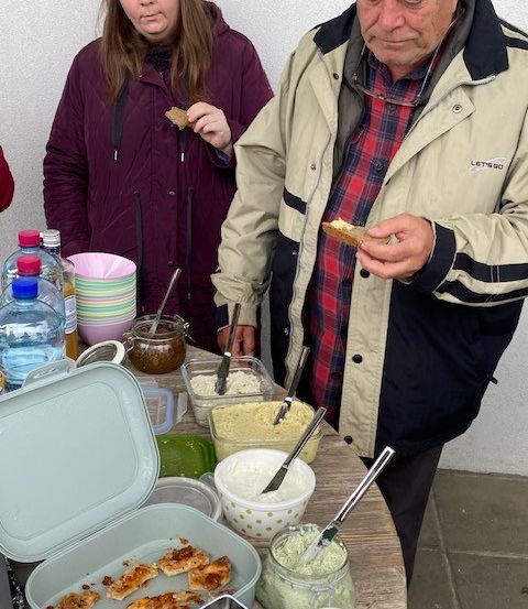 Ein älterer Mann und eine Frau genießen Speisen von einem Buffettisch, umgeben von verschiedenen Gerichten und Beilagen.