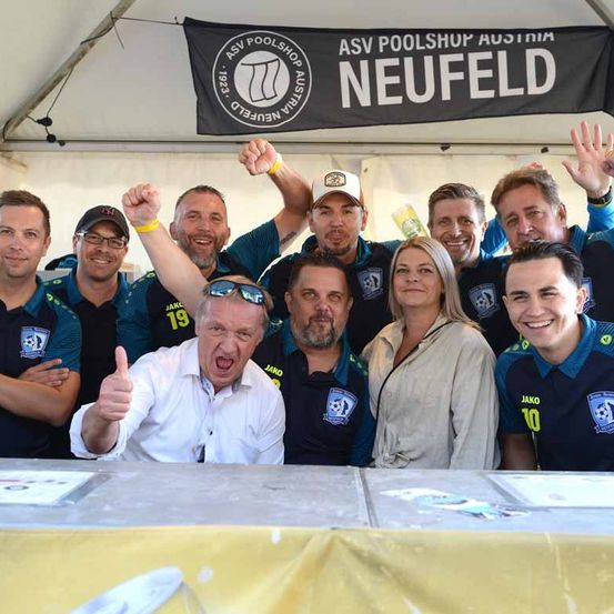 Eine Gruppe von Menschen lächelt und posiert für ein Foto unter einem Banner mit dem Text ASV Poolshop Neufeld.