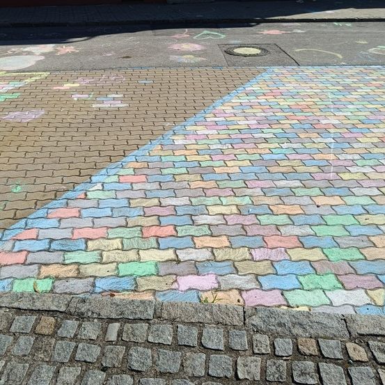 Eine Nahaufnahme eines farbenfrohen Kreidezeichnung auf einem gepflasterten Gehweg mit verschiedenen Formen und Mustern.