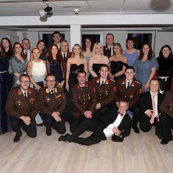 Eine Gruppe von Menschen in Uniformen und formeller Kleidung posiert für ein Foto, möglicherweise für eine besondere Veranstaltung.