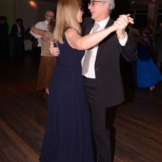 Ein Mann und eine Frau tanzen eng auf einem Holzboden auf einer Party.
