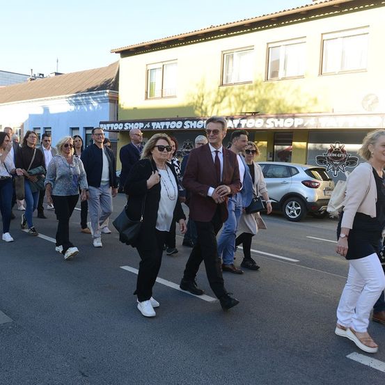 Eine Gruppe von Menschen läuft mitten auf der Straße vor einem Tattoo-Shop.