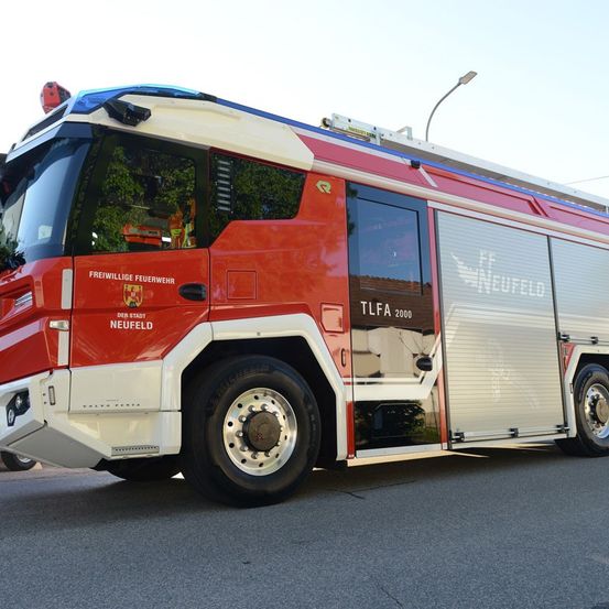 Ein roter Feuerwehrwagen mit der Aufschrift Freiwillige Feuerwehr und TLFA 2000 an der Seite steht auf der Straße.