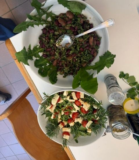 Zwei weiße Salatschüsseln mit einem Löffel in der oberen Schüssel und einer Gewürzflasche auf dem Tisch.