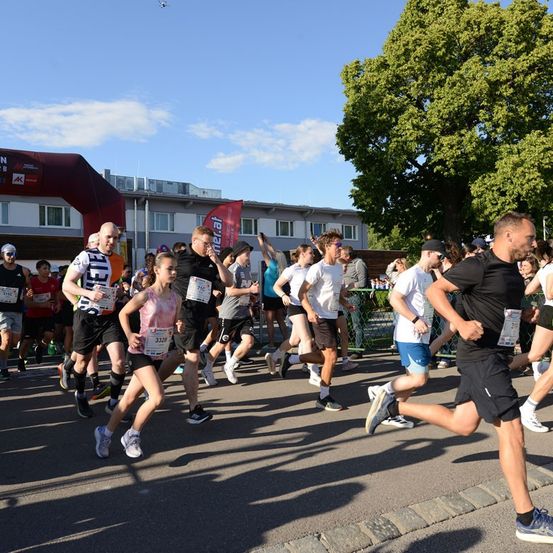 Eine Gruppe von Läufern nimmt an einem Marathon teil und läuft auf einer Straße, während eine Menge Menschen sie anfeuert.