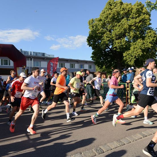 Eine Gruppe von Läufern in verschiedenen Farben und Outfits nehmen an einem Marathon an einem sonnigen Tag teil.