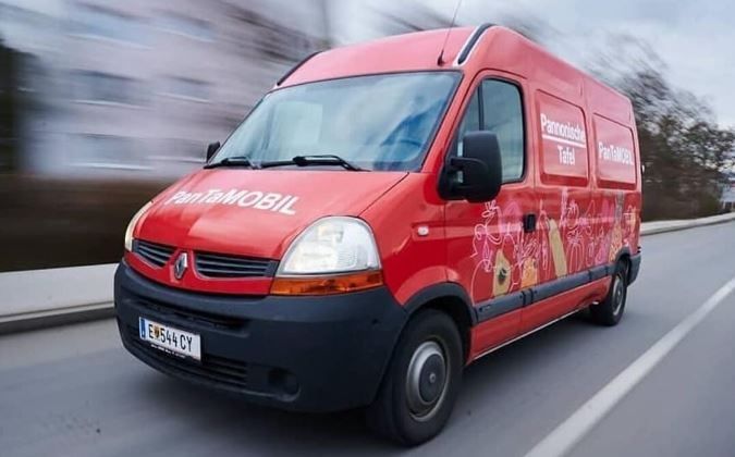 A red Renault van with the words PanTaMOBIL and PanTaTel953L on the side is driving on the road.