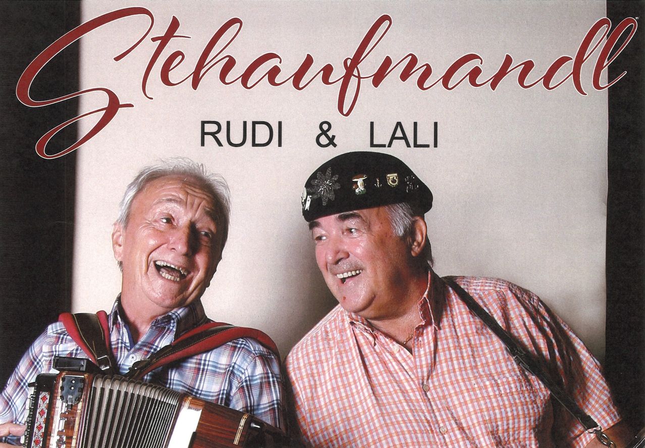 Rudi & Lali mit Steirischer Harmonika und Hut, lachend vor hellem Hintergrund