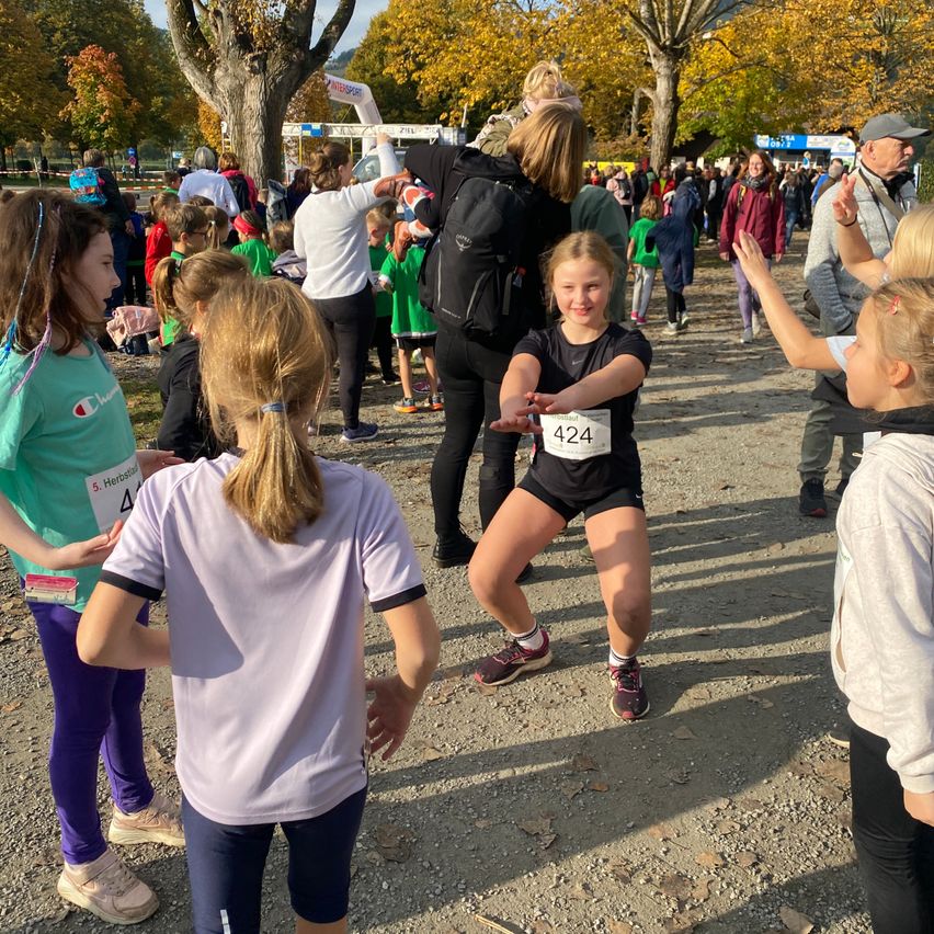 Eine Gruppe junger Läufer nimmt an einem Rennen teil, einer mit der Nummer 424, während andere Zuschauer am Rande zusehen.