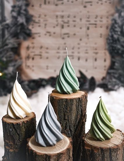 Vier weihnachtsbaumförmige Kerzen stehen auf Baumstümpfen. Dahinter ist ein verschwommener Hintergrund mit Musiknoten und Bäumen.