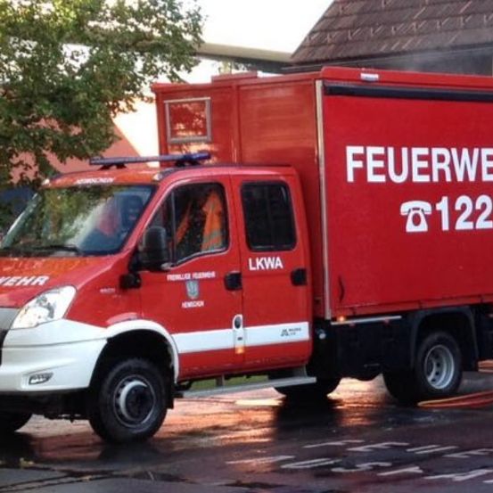 Ein roter und weißer Feuerwehrwagen mit den Worten 'Feuerwehr' und '122' steht vor einem Gebäude.