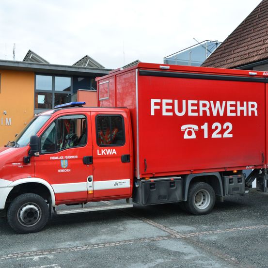 Ein roter Feuerwehrwagen mit 'FEUERWEHR' und '122' darauf steht vor einem Gebäude geparkt.