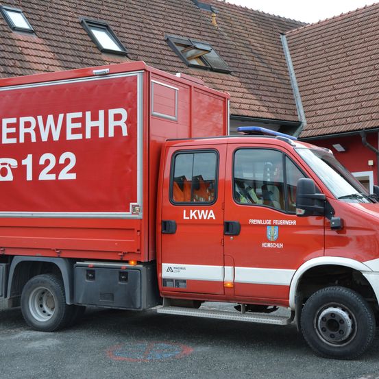 Ein rotes Notfallfahrzeug mit der Aufschrift Wehrwehr und der Nummer 122 steht vor einem Gebäude. Das Fahrzeug hat oben ein blaues Licht und eine weiße Linie an der Seite.