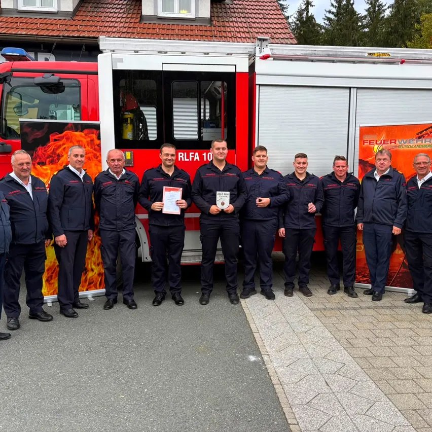 Eine Gruppe von Feuerwehrleuten posiert für ein Foto vor einem Feuerwehrauto.