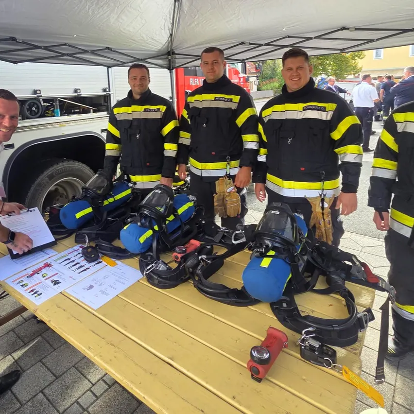Eine Gruppe von Feuerwehrleuten in Uniform steht neben einem Tisch mit Ausrüstung darauf.