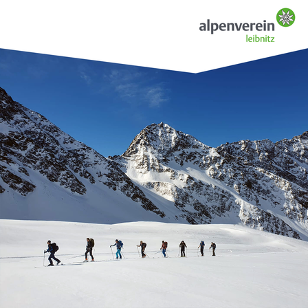 Eine Gruppe von Skifahrern im Schnee, mit Bergen im Hintergrund. Das alpenverein-Logo ist oben sichtbar.
