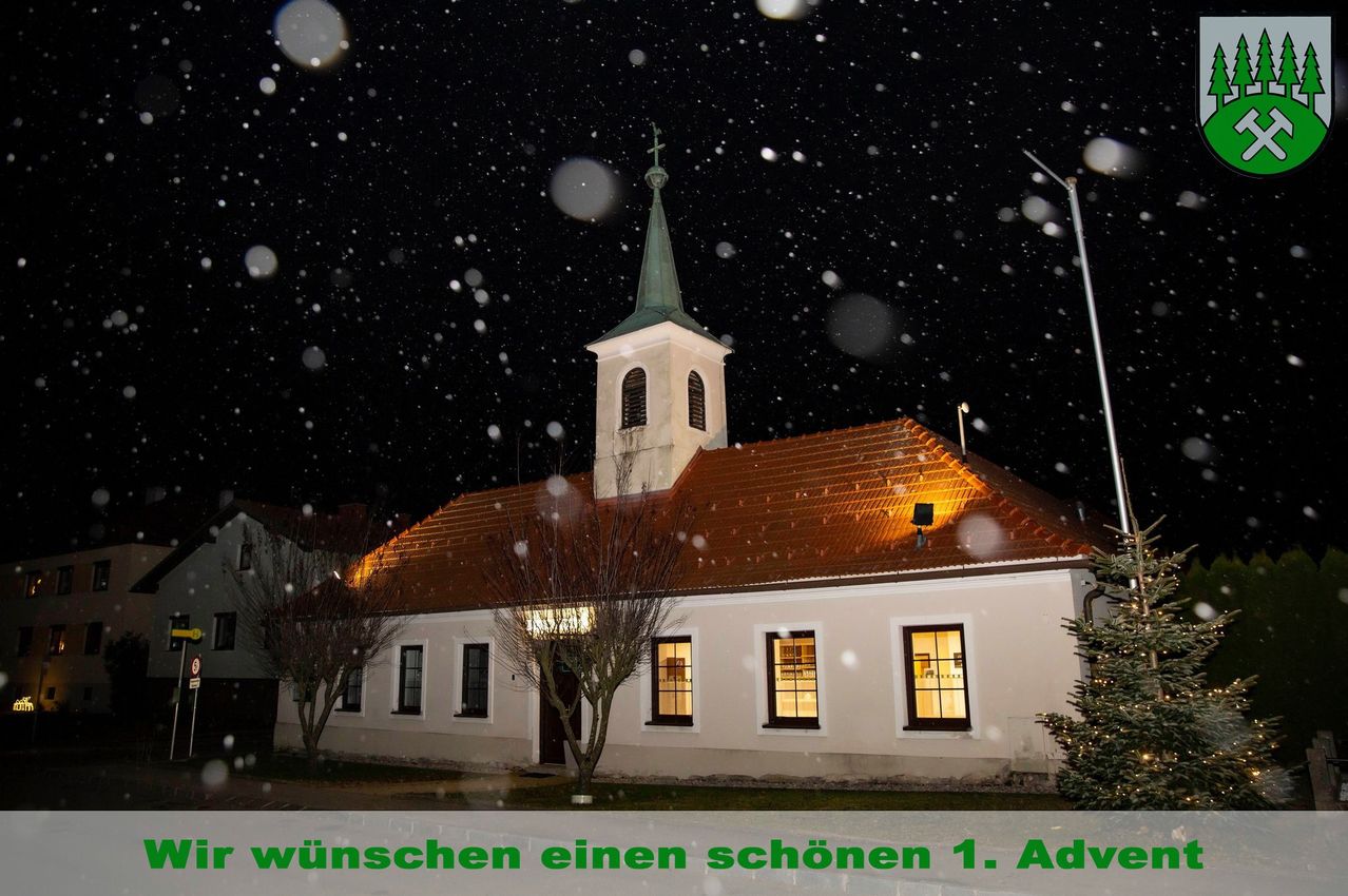 Eine Kirche mit einem Kirchturm und einem braunen Dach ist in der Nacht während eines Schneesturms beleuchtet. Sie hat ein großes Fenster an der Vorderseite, eine kleine Tür und einen Baum davor.