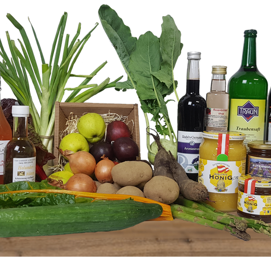 Eine Sammlung von Gemüse, Früchten und Gewürzen ist auf einer Holzoberfläche ausgestellt. Das Sortiment umfasst grüne Blattgemüse, Zwiebeln, Kartoffeln und eine Gurke.