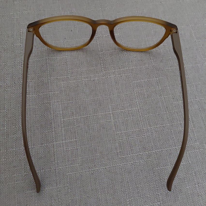 A pair of brown-framed glasses with clear lenses, resting on a light gray fabric surface.