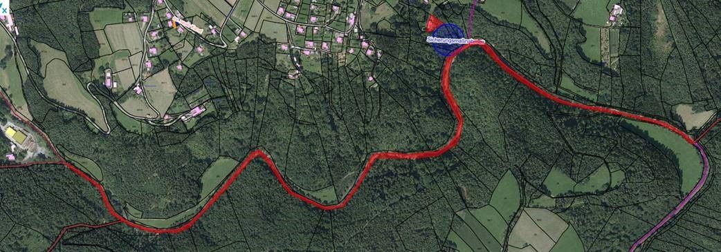 Eine Luftaufnahme eines ländlichen Gebiets mit einer sich schlängelnden roten Linie, die einen Weg durch die Landschaft markiert.