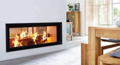 A modern fireplace with a burning log is mounted on a white wall. To the right, there is a wooden dining table and a bench. A wooden cabinet is near the window.