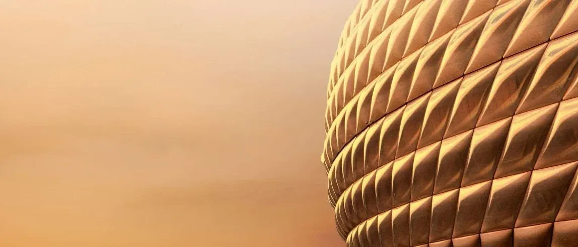 Eine Nahaufnahme einer goldenen, geometrischen Struktur mit strukturierter Oberfläche. Die Struktur hat eine Reihe von rautenförmigen Mustern.