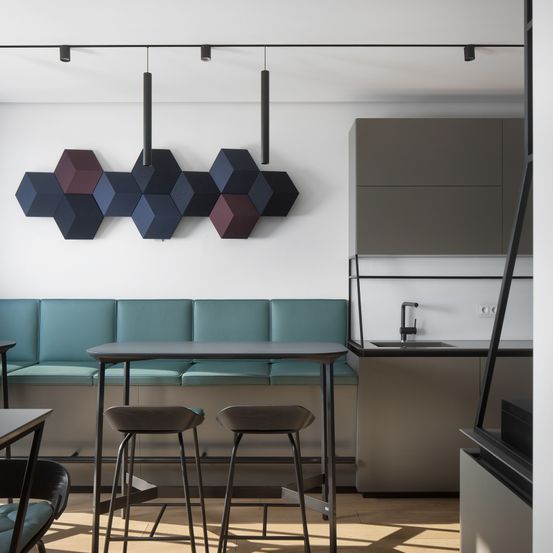 Eine moderne Küche mit sechseckigem Design an der Wand, einer türkisfarbenen Bank, einem Holzboden und einem Waschbecken mit Wasserhahn.