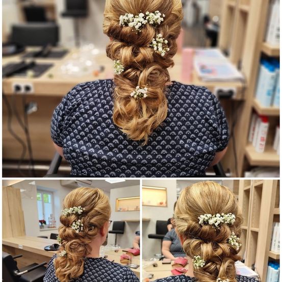 Eine Frau mit blondem Haar, das zu einem Dutt mit weißen Blumen gebunden ist, sitzt in einem Salon.