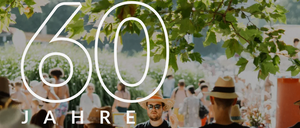 Ein Poster, das 60 Jahre Freibad Furstenfeld feiert, zeigt mehrere Menschen in Hüten, die 'Freibad Furstenfeld' in großen weißen Buchstaben lesen. Der Hintergrund ist verschwommen mit Menschen, Pflanzen und einem Baum.