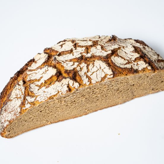 Ein rustikales, vollwertiges Brot mit knuspriger Kruste und heller, luftiger Krume. Es hat einen leicht goldenen Farbton und eine rissige, strukturierte Oberfläche.