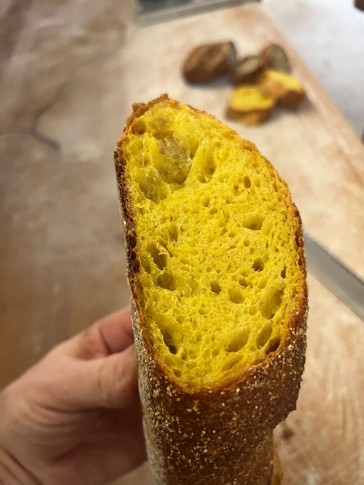 Ein Nahaufnahme eines geschnittenen Stücks Brot mit sichtbarer Krumenstruktur und goldener Kruste. Das Brot hat ein rustikales Aussehen mit einer rauen Textur.