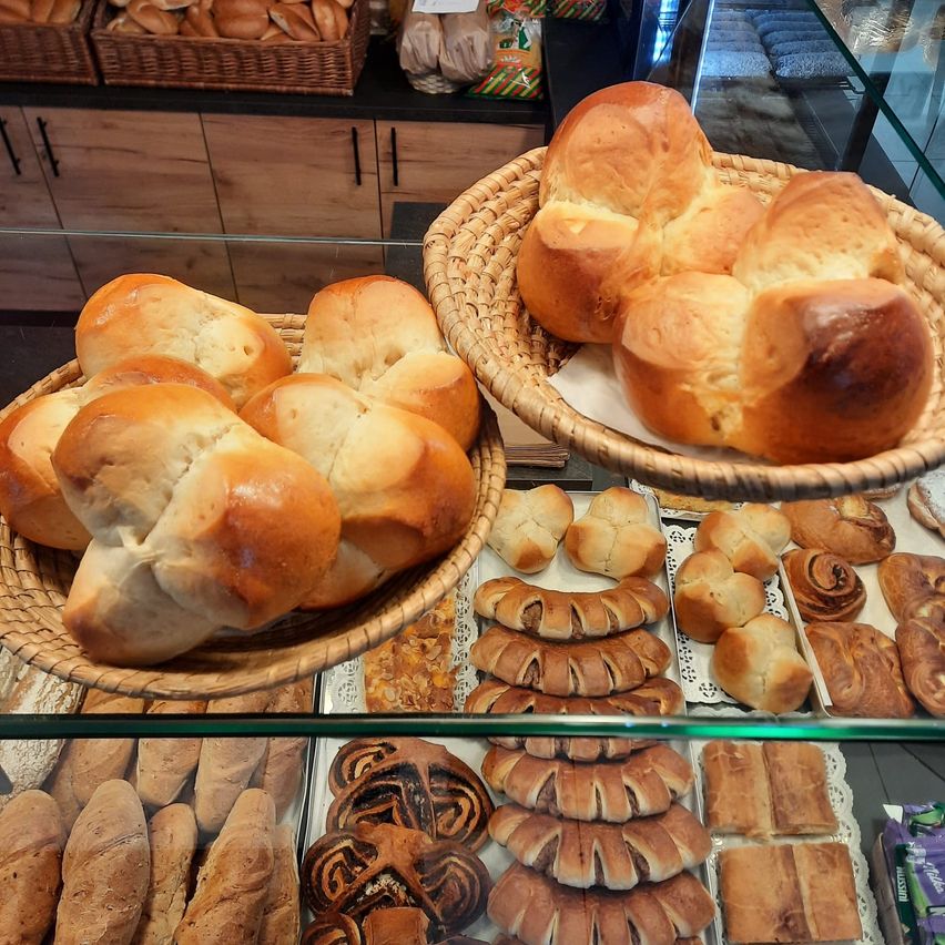 Eine Vitrine mit verschiedenen Broten. Es gibt zwei Körbe mit gezwirnten Broten und eine Auswahl an Gebäck und Brötchen.