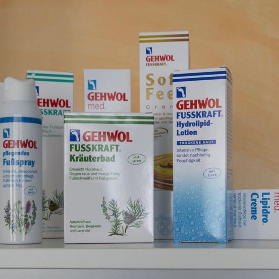 Eine Sammlung von Gehwol Fußpflegeprodukten, einschließlich Lotion, Creme und Spray, auf einem Regal ausgestellt. Die Produkte haben pflanzliche und blumige Bilder auf ihren Verpackungen.