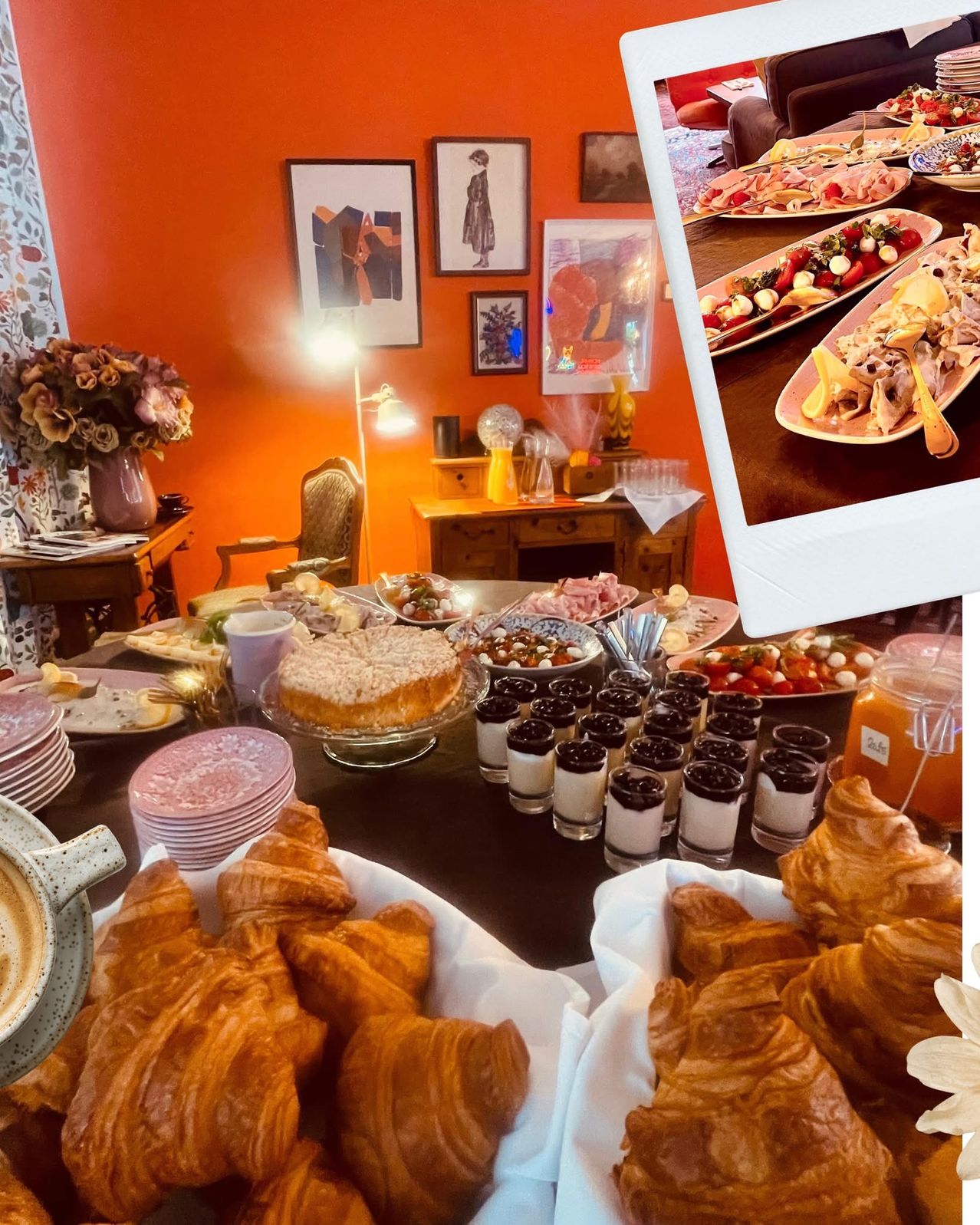 Ein Esstisch mit einem Buffet-Setup, einschließlich Croissants, Desserts und herzhaften Gerichten. Dekoriert mit Blumen und gerahmter Kunst an einer orangefarbenen Wand.