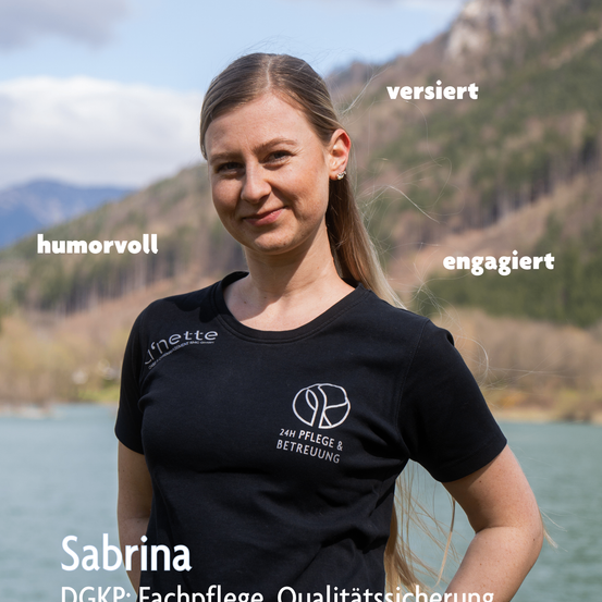 Eine Frau namens Sabrina, gekleidet in einem schwarzen Shirt mit Logo, steht am See mit Bergen im Hintergrund. Sie hat einen fröhlichen Ausdruck und ist umgeben von Wörtern wie 'humorvoll' und 'engagiert'.