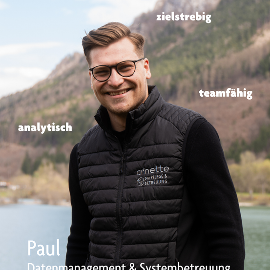 Ein lächelnder Mann in einer schwarzen Jacke mit 'Arnette' darauf, steht vor einem See mit Bergen im Hintergrund. Wörter wie 'zielstrebig', 'teamfähig' und 'analytisch' sind um ihn herum geschrieben.