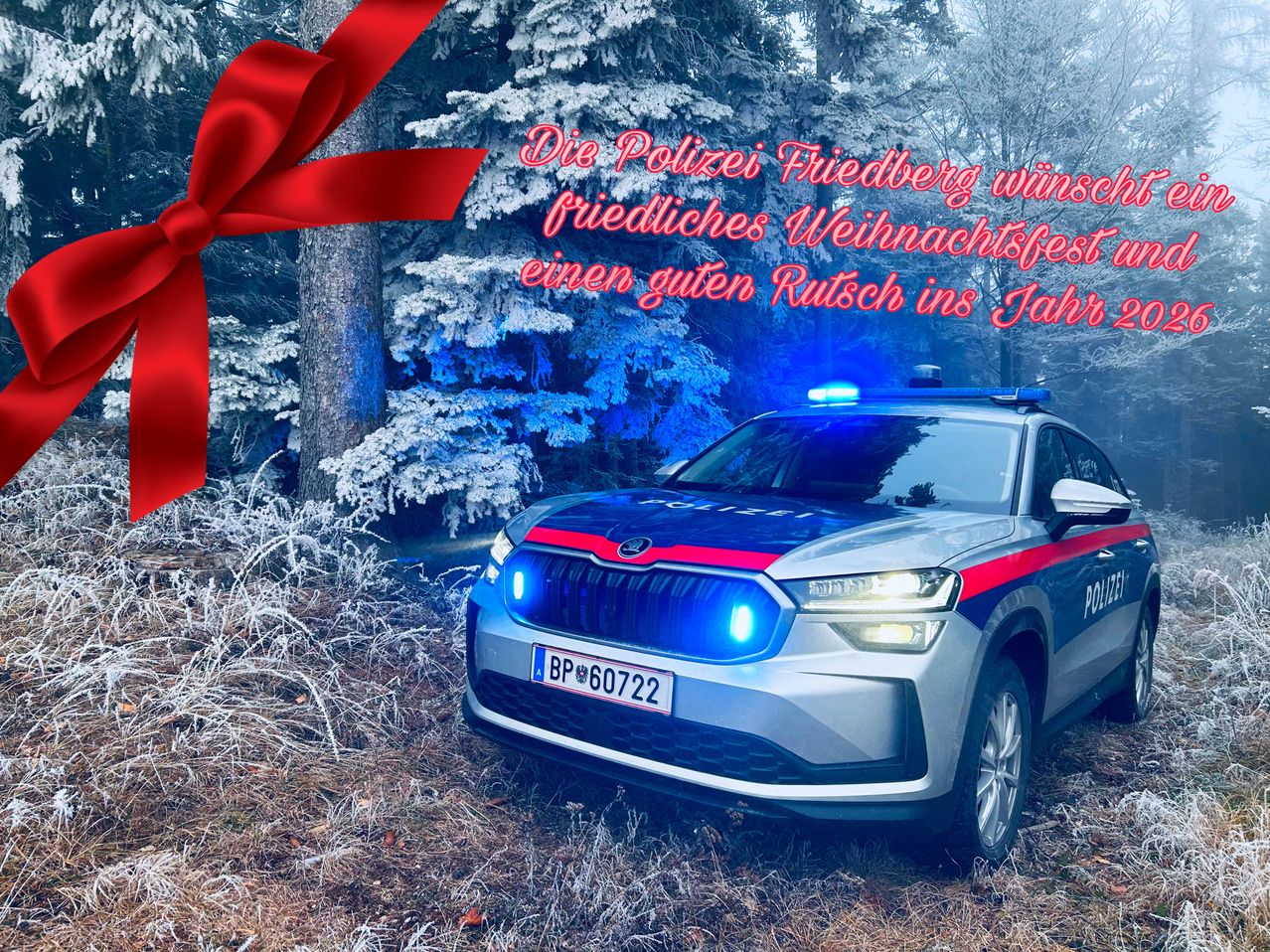 Ein Polizeiauto mit blauen Lichtern steht in einem verschneiten Bereich, mit einem Band und einer Botschaft, die ein friedliches Weihnachtsfest und eine gute Erholung für das Jahr wünscht.