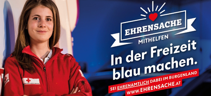 Eine lächelnde Frau in einem roten Jackett steht vor einem blauen Hintergrund mit einem roten Herz und dem Text 'EHRENSACHE MITHELFEN In der Freizeit blau machen.' und einer Website-URL.